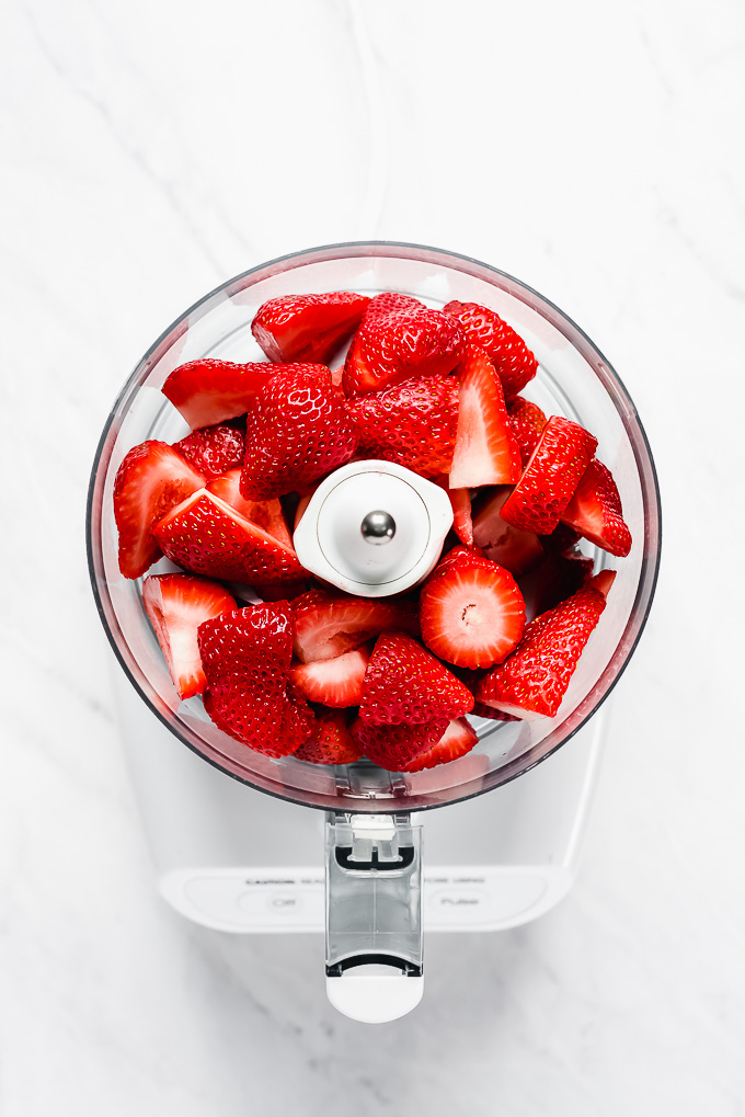 Strawberries with stems removed in a food processor.