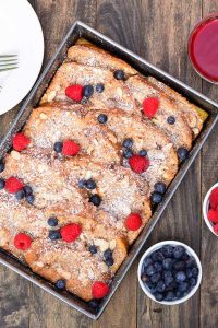 French toast casserole baked with a coconut almond puree and served with fresh berries and raspberry sauce