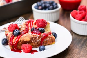French toast casserole baked with a coconut almond puree and served with fresh berries and raspberry sauce