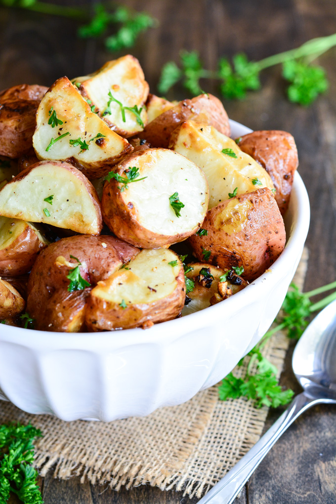 A serving bowl of Roasted Red Potatoes topped with parsley.