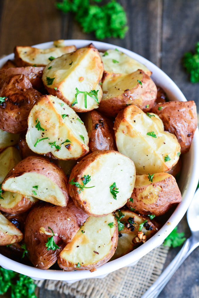 Close up of Garlic Roasted Red Potatoes with browned edges in a serving bowl.