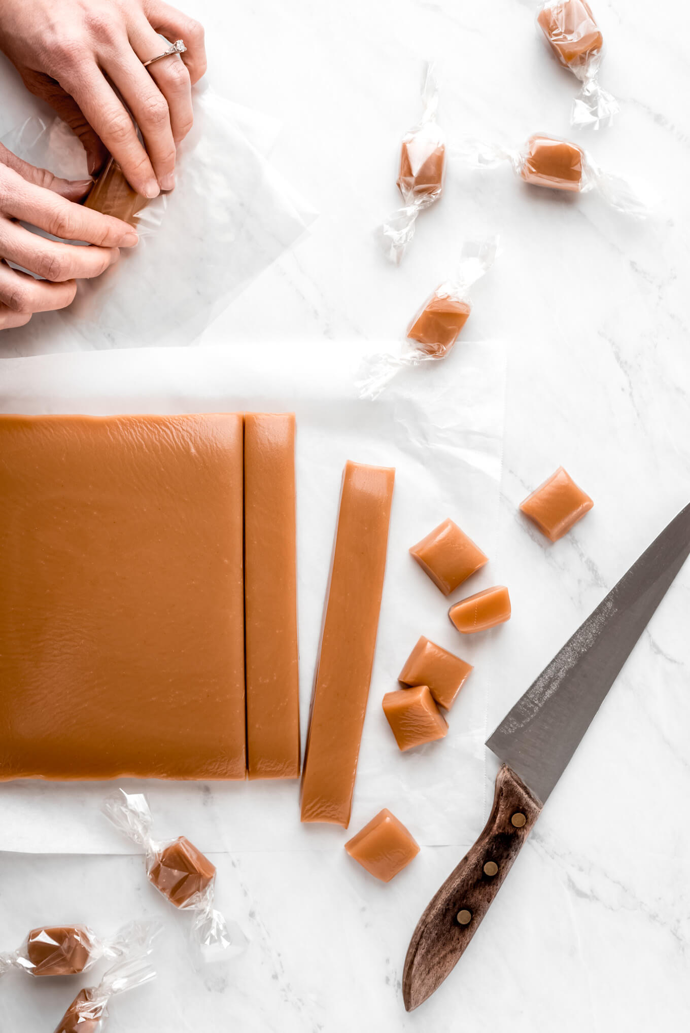 A large slab of caramel cut up into long strips and squares and some wrapped in cellophane.