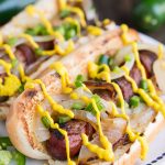 Hot dogs wrapped in bacon and topped with grilled onions, jalapenos, and Heinz Mustard
