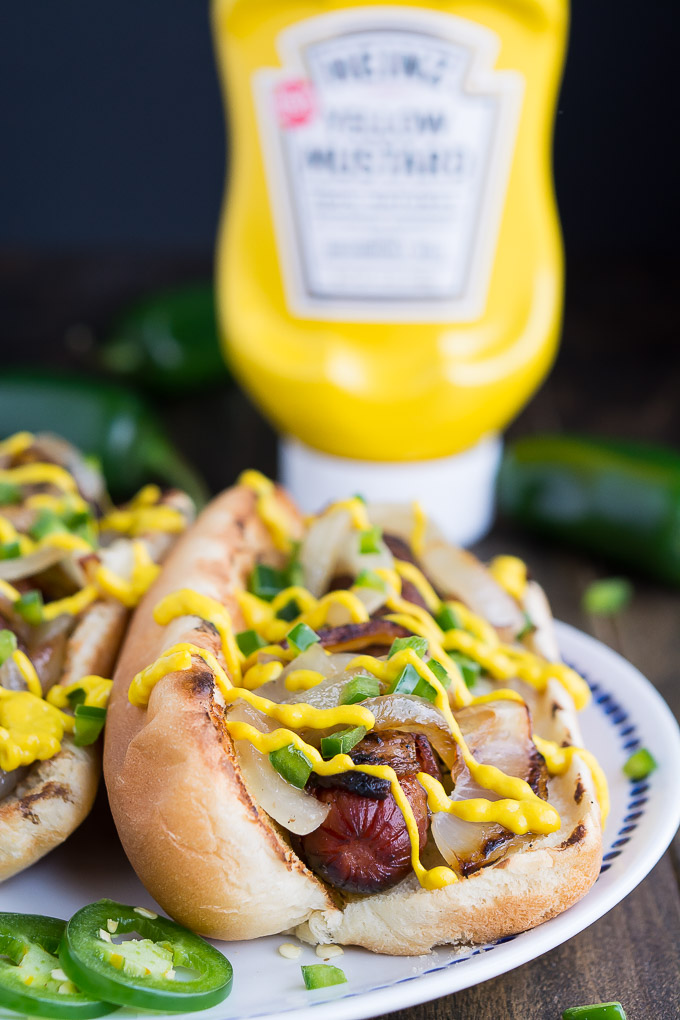 Hot dogs wrapped in bacon and topped with grilled onions, jalapenos, and Heinz Mustard