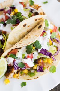 Tacos filled with spiced pan-seared tilapia, cabbage, lettuce, corn, and pico de gallo