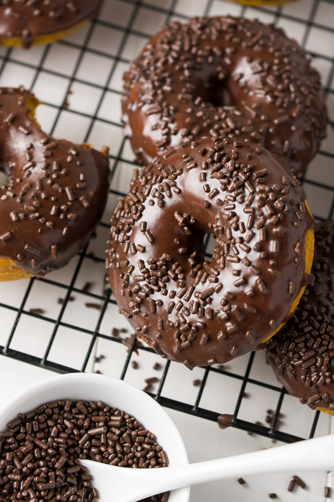 Baked pumpkin doughnuts topped with chocolate icing and chocolate sprinkles.