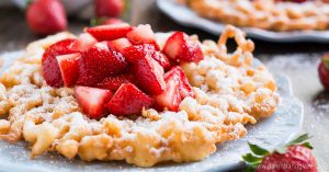 Bring the state fair to your home with these crisp and tender FUNNEL CAKES coated in powdered sugar and fresh strawberries!