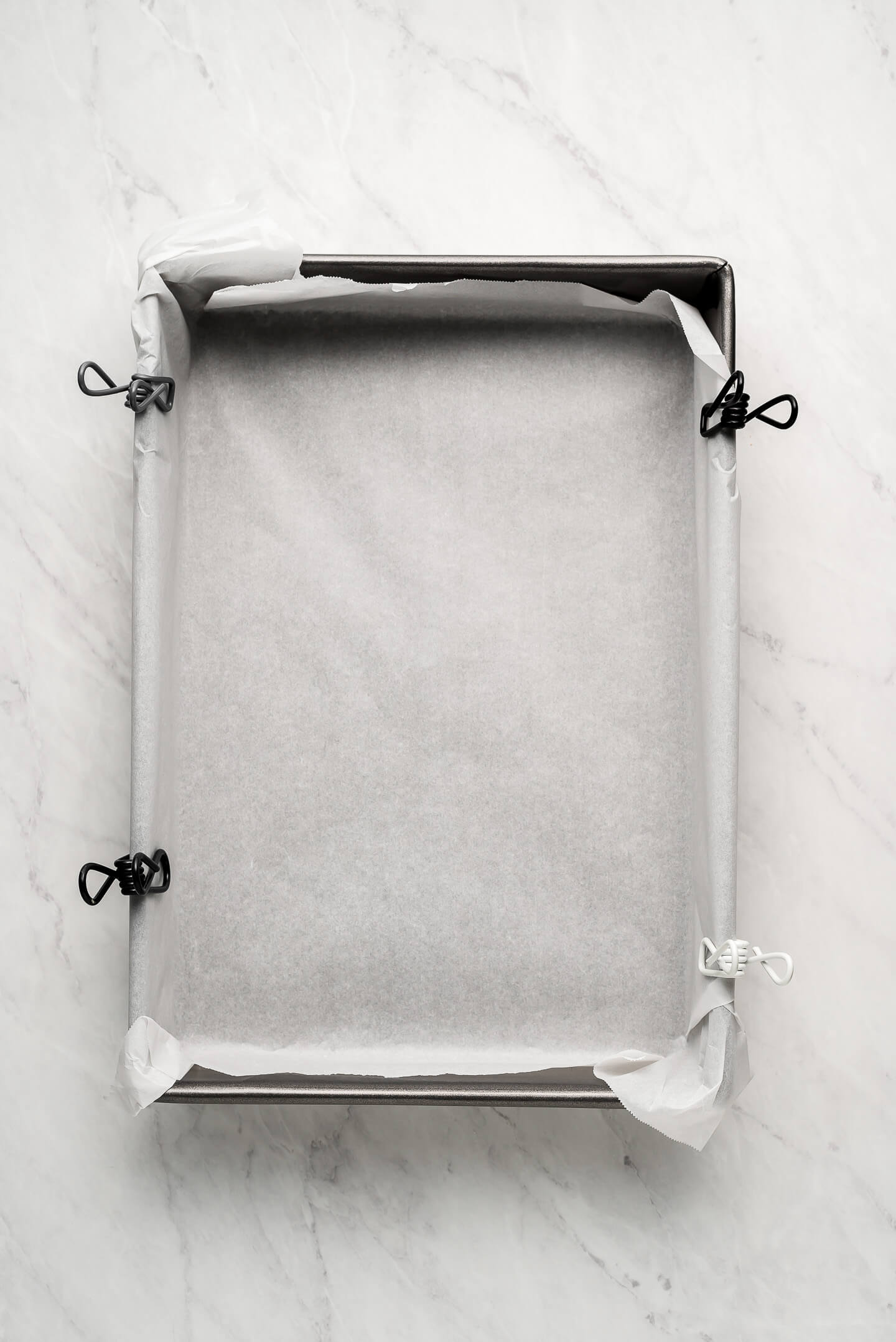 9x13 inch pan lined with parchment paper with chip clips holding it on the sides.