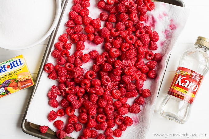 Raspberries on a tray with pectin, corn syrup, and sugar to the sides.
