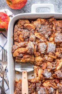 Overnight Apple French Toast Casserole in a 9x13 inch pan, dusted with powdered sugar and sliced into 12 pieces.