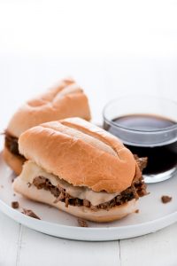 Dinner just got better with these Slow Cooker French Dip Sandwiches with hearty beef and melted provolone cheese on a toasted bun and dipped in au jus.