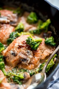 Cast iron skillet with One Skillet Chicken and Broccoli in it, covered in a garlic mushroom cream sauce.