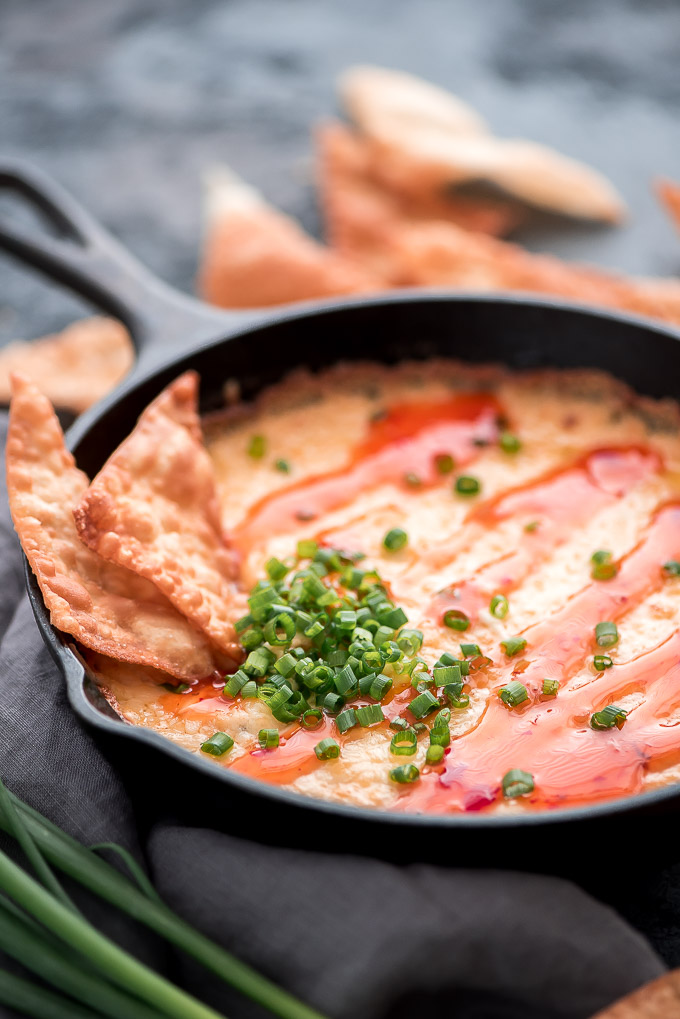 Skillet of Crab Rangoon Dip topped with Sweet Thai Chili sauce and green onions.