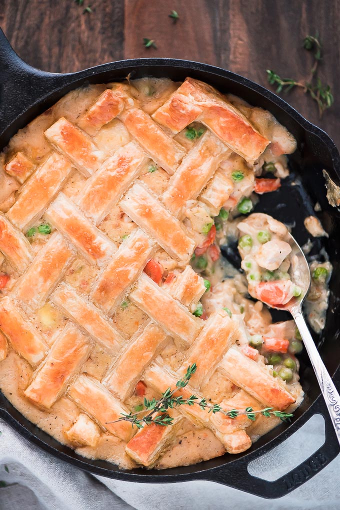 Easy Chicken Pot Pie in a skillet scooped into, showing the chicken, carrot, and pea filling.