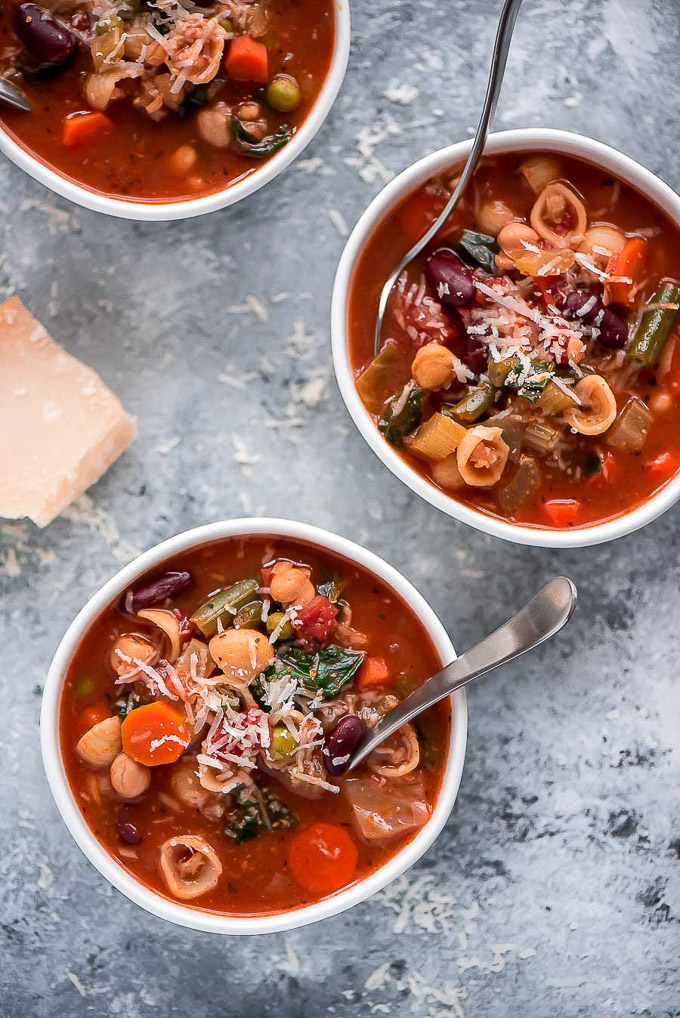 Multiple bowls of Minestrone Soup sprinkled with Parmesan cheese.