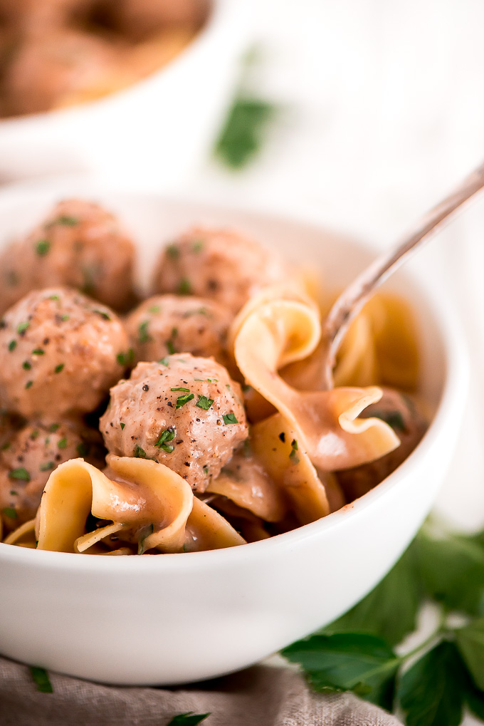 A Swedish Meatball and egg noodles on a fork ready to take a bite.