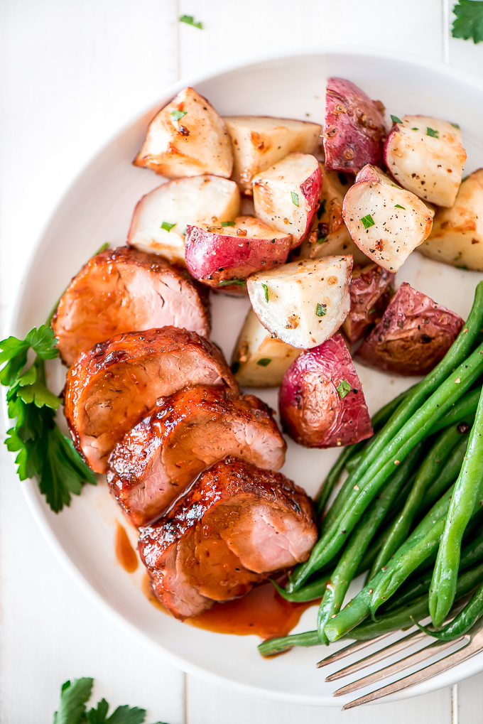 Pork tenderloin on a plate with roasted garlic potatoes and green beans.
