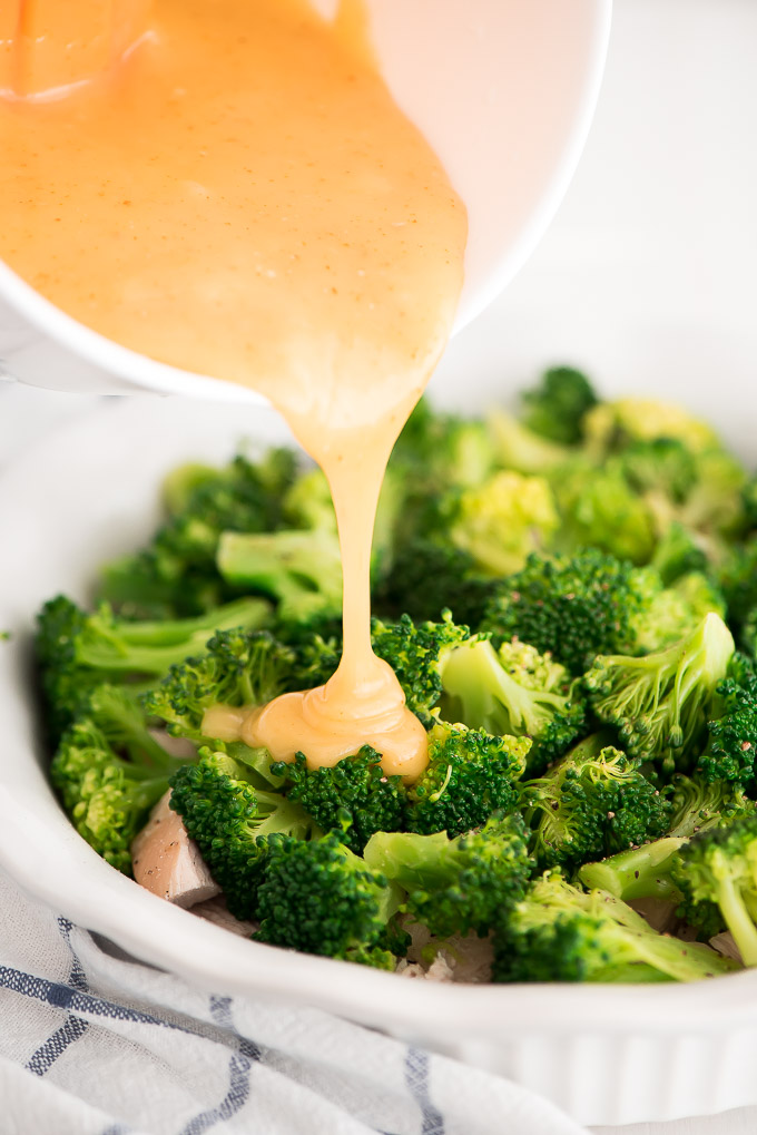 Pouring curry sauce over broccoli to make Chicken Divan.