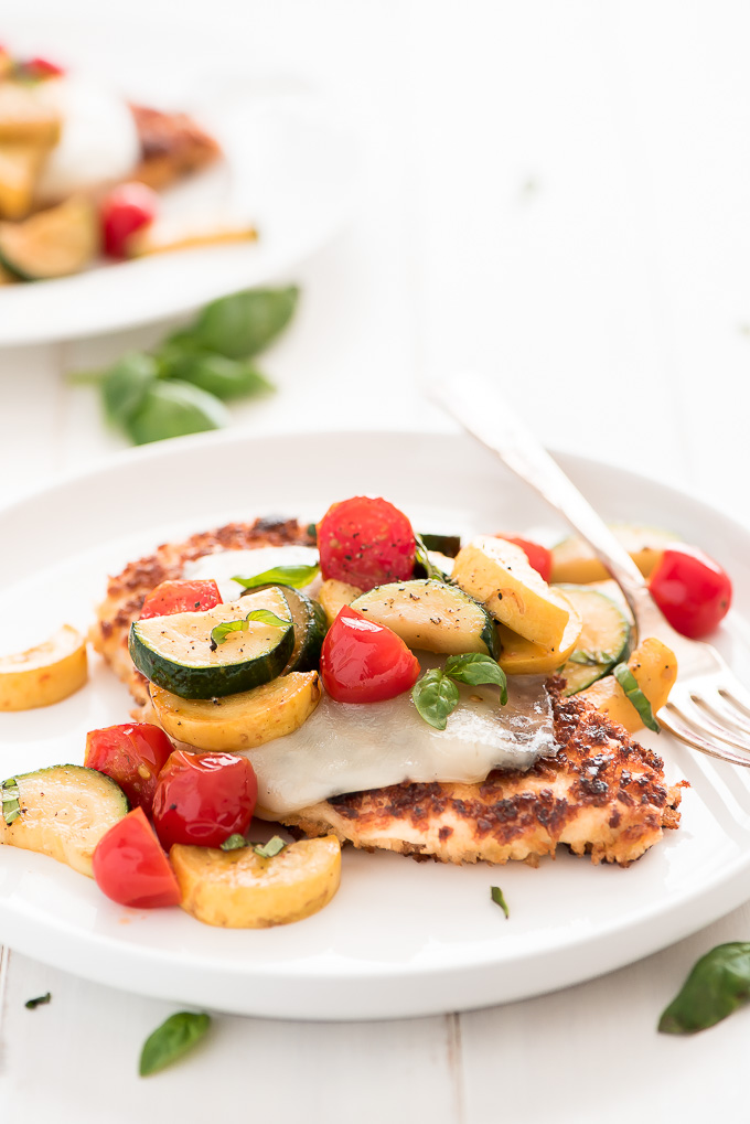 Summer Parmesan Chicken topped with mozzarella cheese, zucchini, summer squash, tomatoes, and fresh basil.