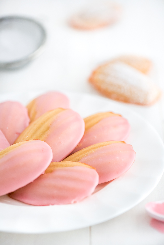 Pink glazed French Madeleines on a plate.