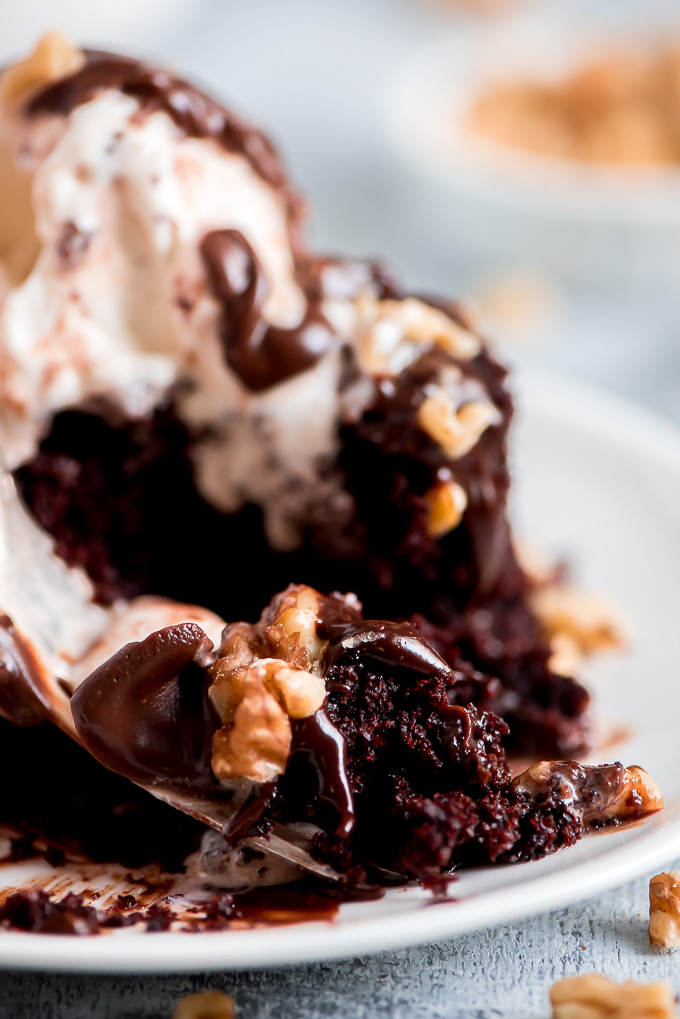 Close up of a fork full of moist Chocolate Mayonnaise Cake topped with fudge and walnuts.