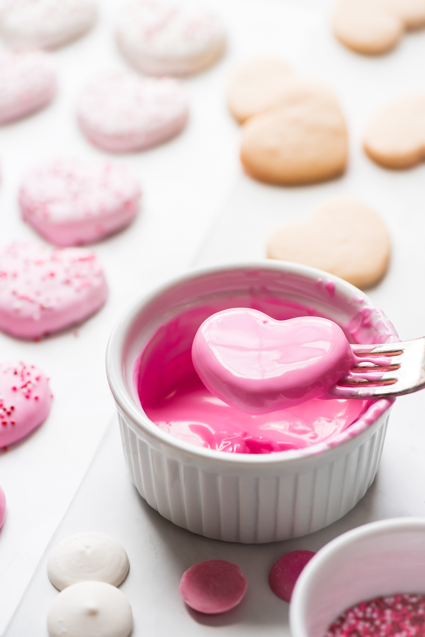 Removing a pink chocolate coated Heart Circus Cookie from a bowl with a fork.