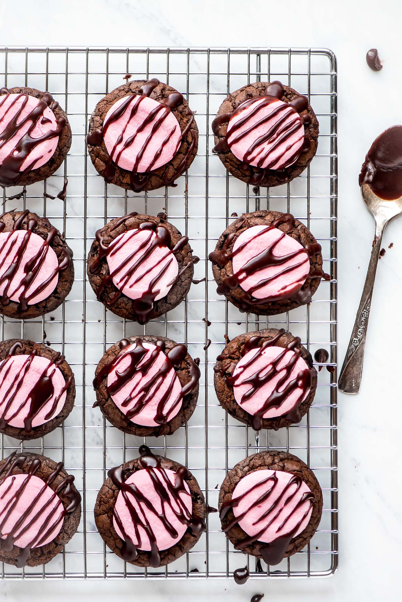 Pink Chocolate Marshmallow Cookies drizzled with chocolate icing, sitting on a cooling rack.