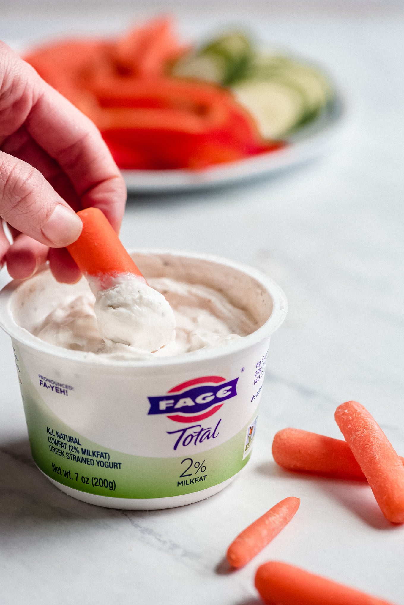 Dipping a carrot into a container of 2-Ingredient Ranch Dip.