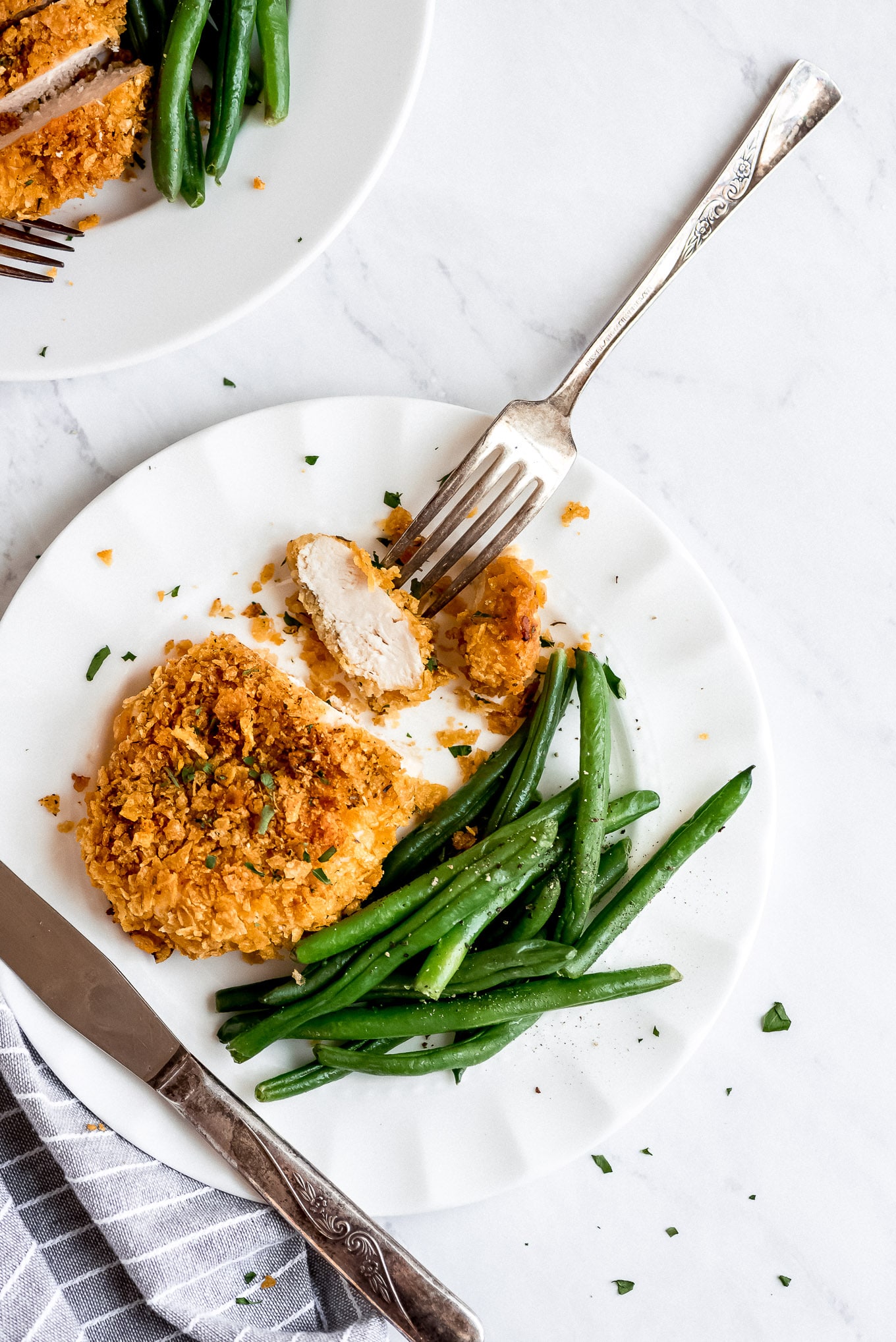 Crispy Chicken half eaten on a plate with green beans.