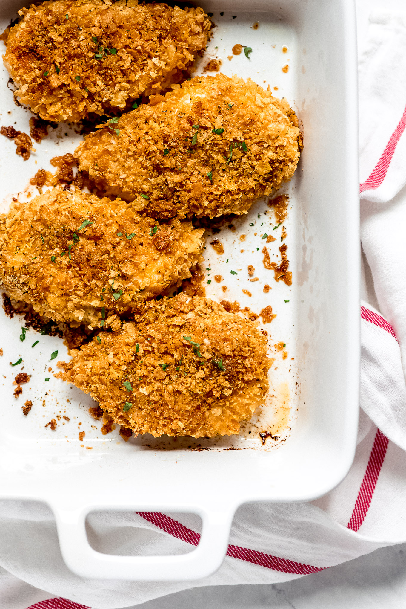 Crispy Baked Chicken with cornflake crispy coating in a white baking dish.