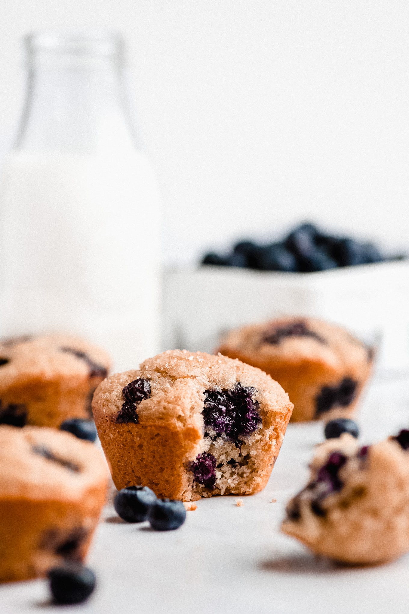 Greek Yogurt Blueberry muffins with a bite taken out of one to show the bursting blueberries inside.