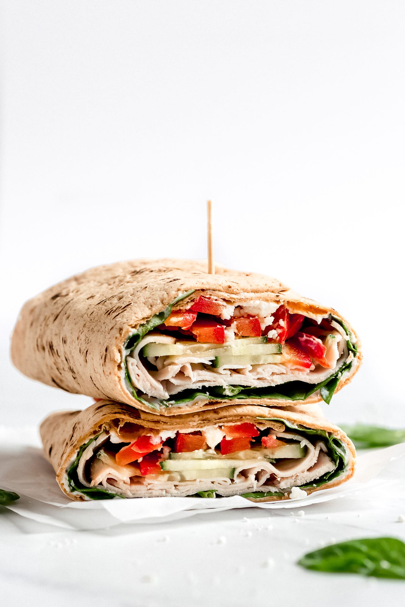 Two halves of a Turkey Ranch Wrap are stacked on top of each other showing the inside full of veggies, turkey, and a Greek yogurt ranch sauce.
