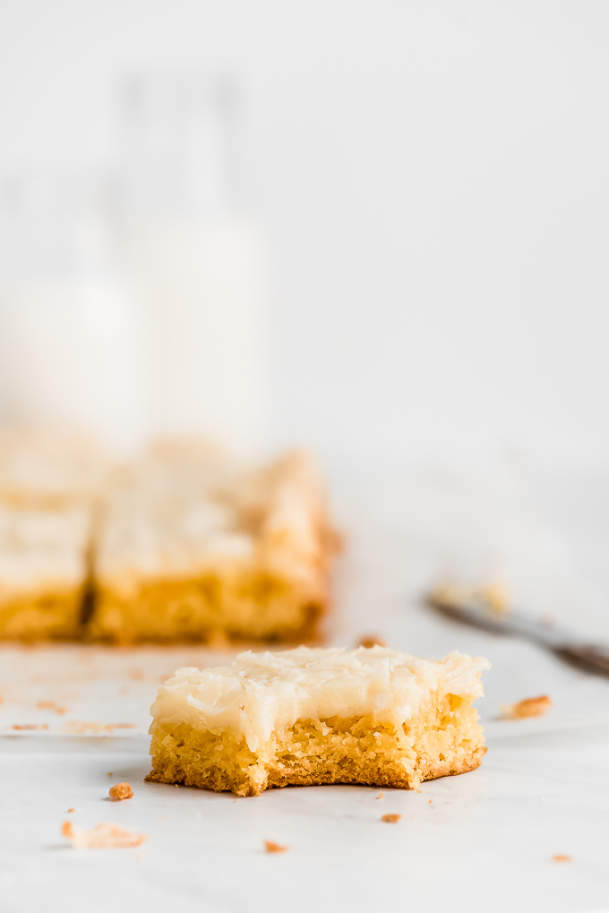 A close up of a square piece of Gooey Butter Cake with a bite taken out showing the bottom cakey layer and gooey top layer.
