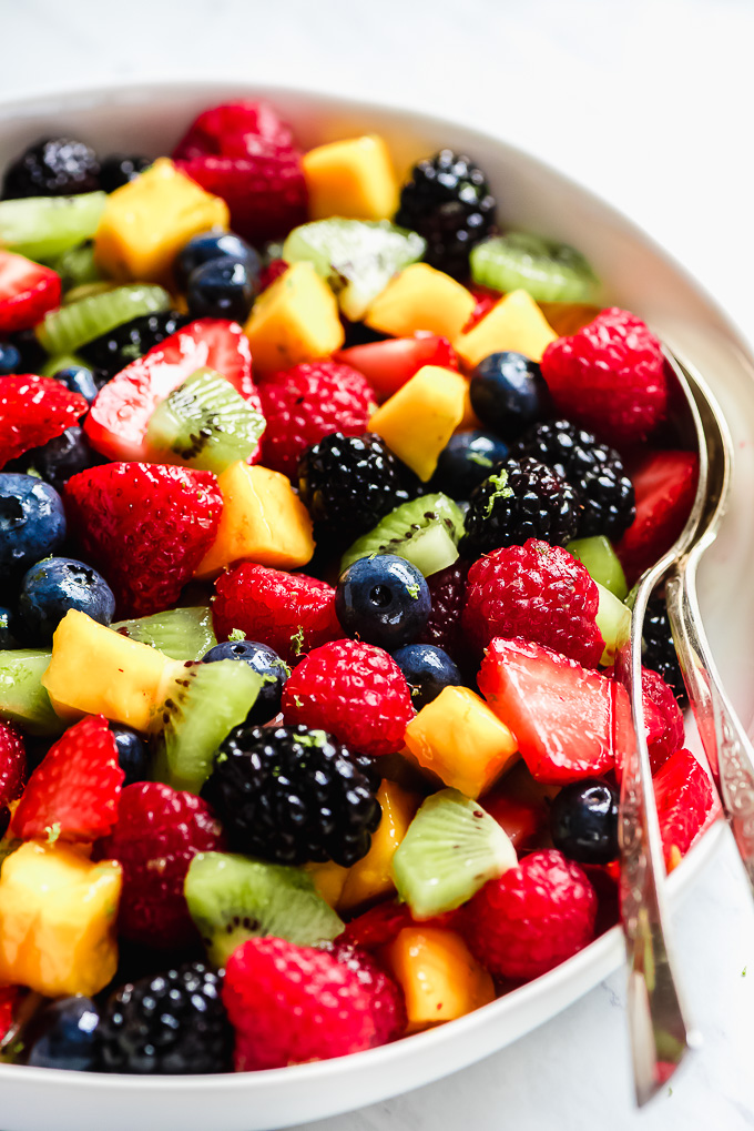 Close up photo of Summer Fruit Salad filled with berries, kiwi, and mangoes in a bowl.