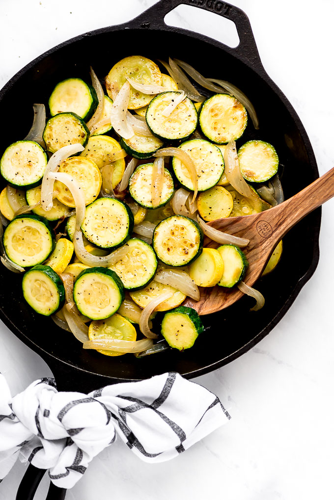 Sautéed Zucchini and Summer Squash in a skillet with a spoon in the pan ready to lift some out.
