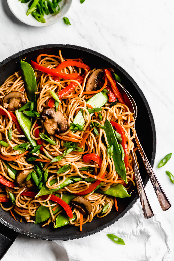 Vegetable Lo Mein in a pan with two spoons on the side.