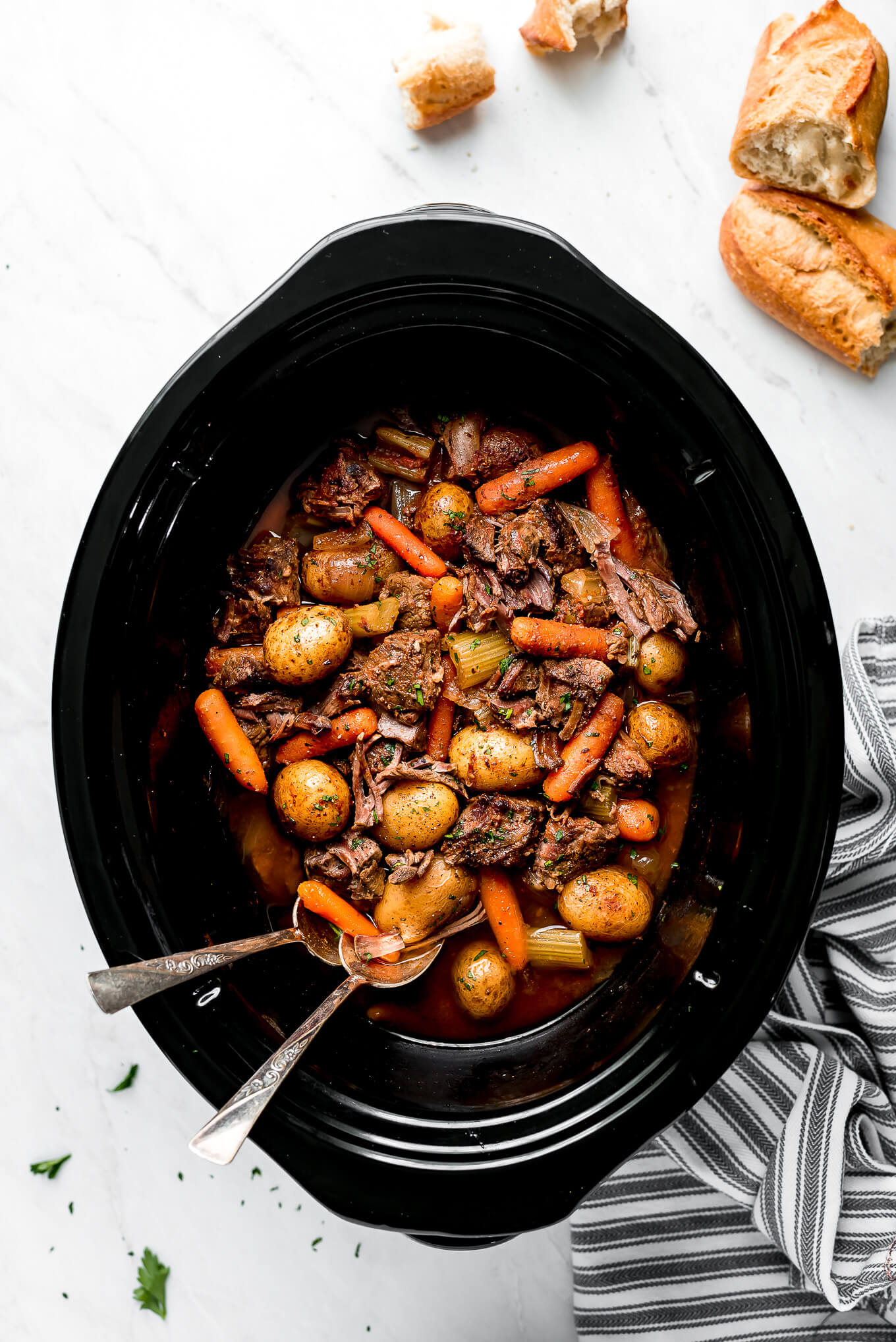 Beef Stew Crockpot meal in a slow cooker with crusty bread on the side.