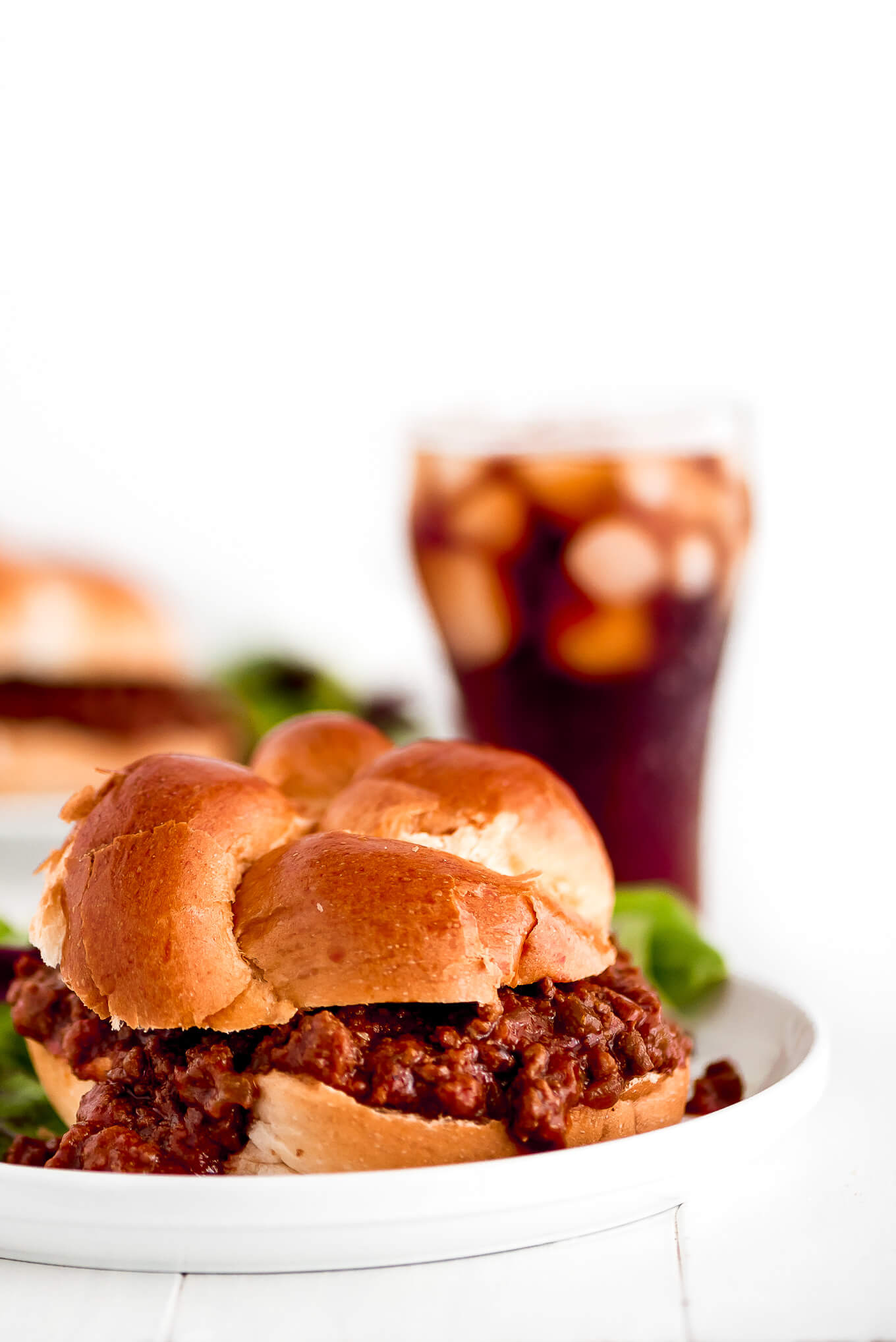 Instant Pot Sloppy Joes on a challah bun with a soda in the background.