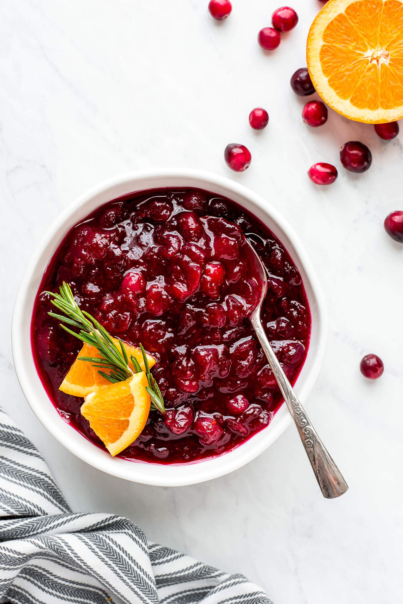Cranberry relish in a bowl garnished with orange slices and rosemary.