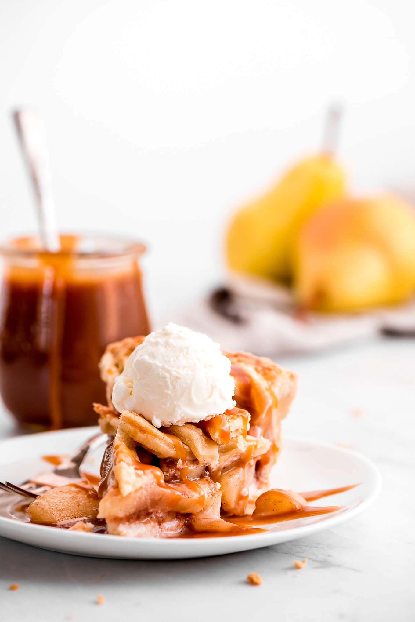 A slice of Pear Pie with caramel sauce and vanilla ice cream on top.