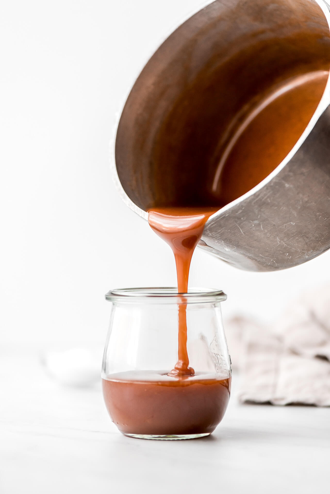 Pouring caramel into a glass jar.