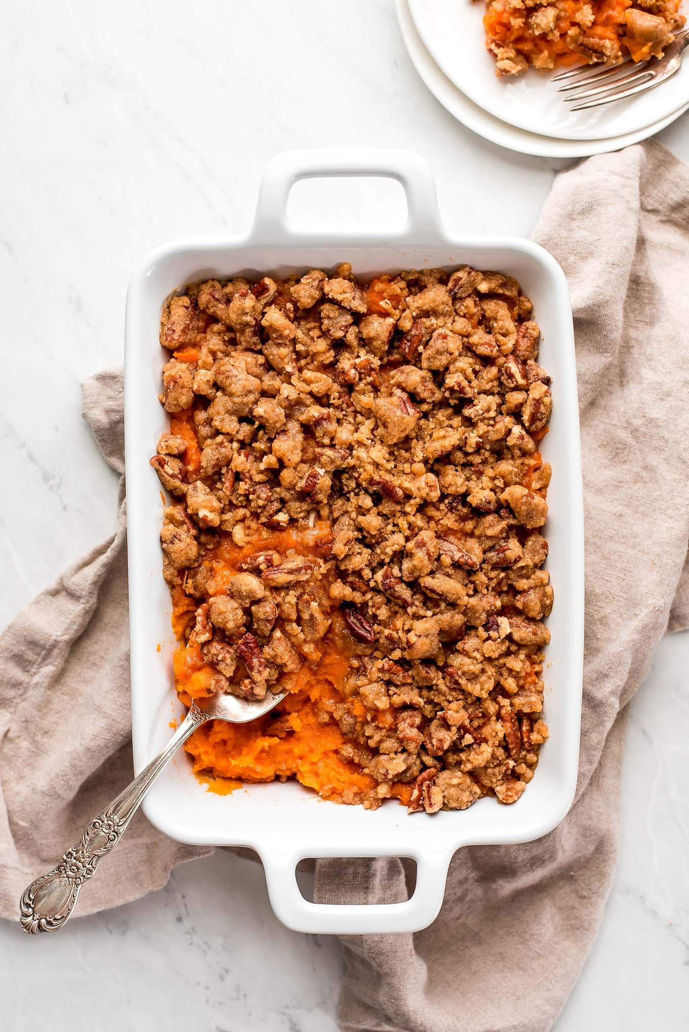 Top view of a sweet potato casserole on top of a napkin and a plate with a serving on it at the side.