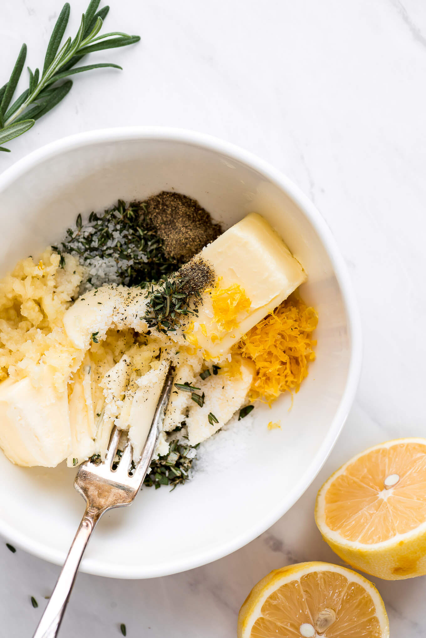 Butter, herbs, garlic, and lemon in a bowl.