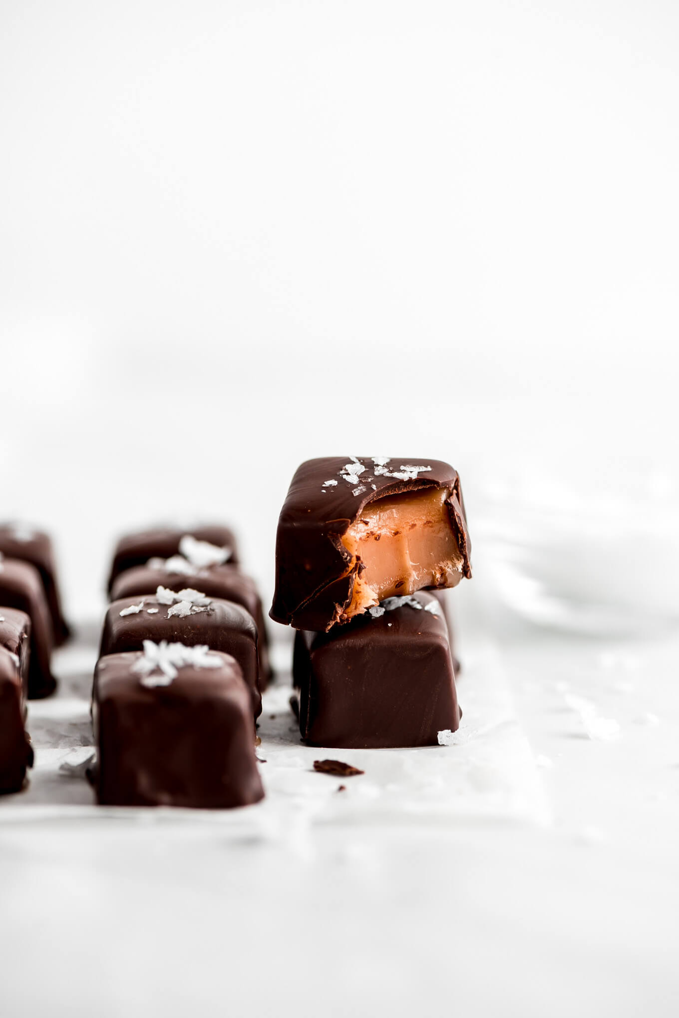 Salted Chocolate Covered Caramels stacked on top of each other with a bite taken out.