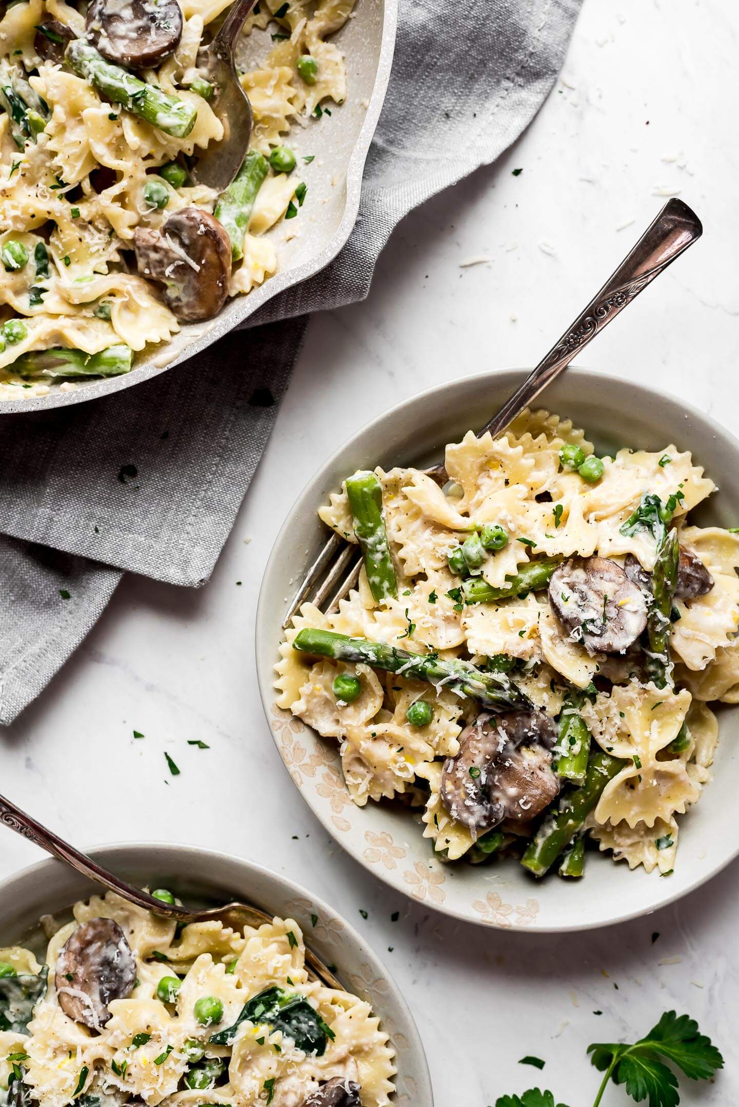 Two bowls and one pan of Creamy Lemon Asparagus Pasta.