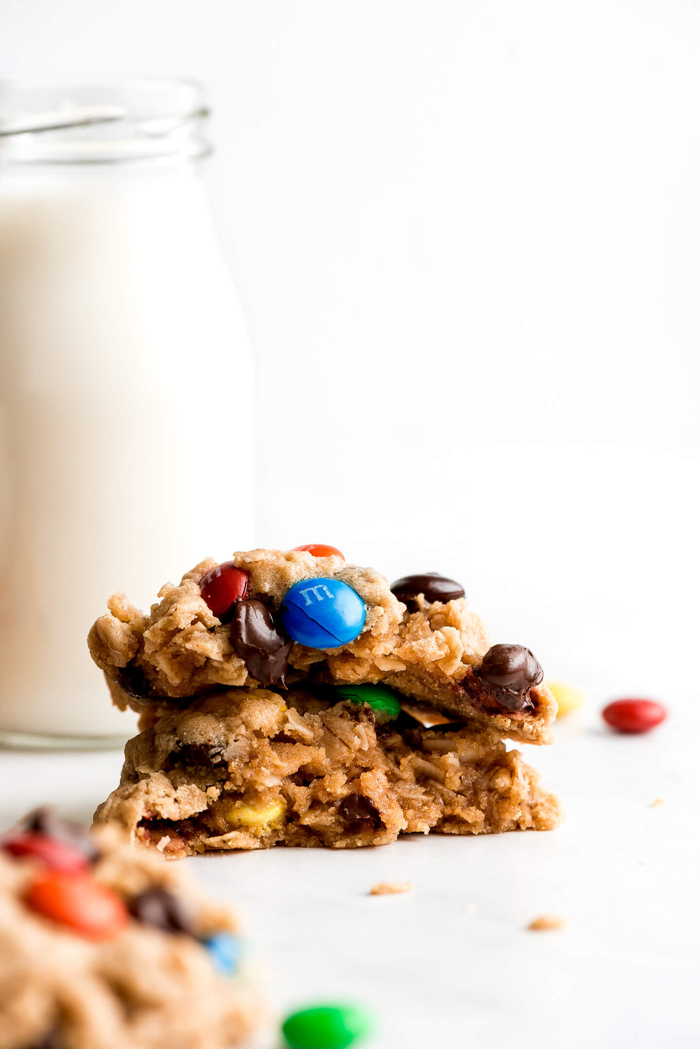 Two halves of a cookie with m&m's and chocolate chips stacked on top of each other showing the chewy inside.
