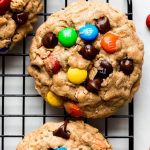 Monster Cookies on a cooling rack with chocolate chips and m&m's pressed into the tops.