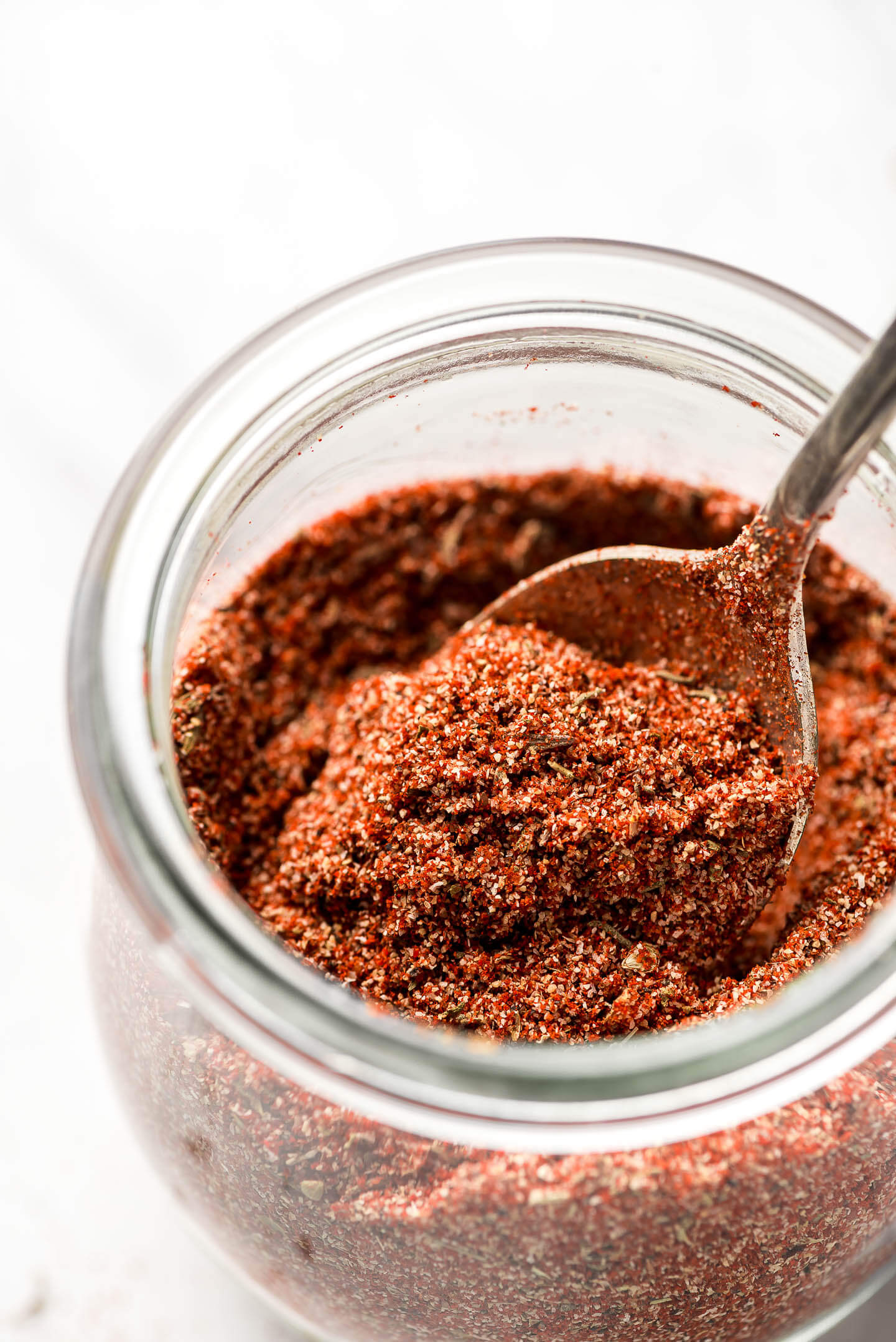 A close up shot of a spoon lifting out Homemade Cajun Seasoning from a jar.