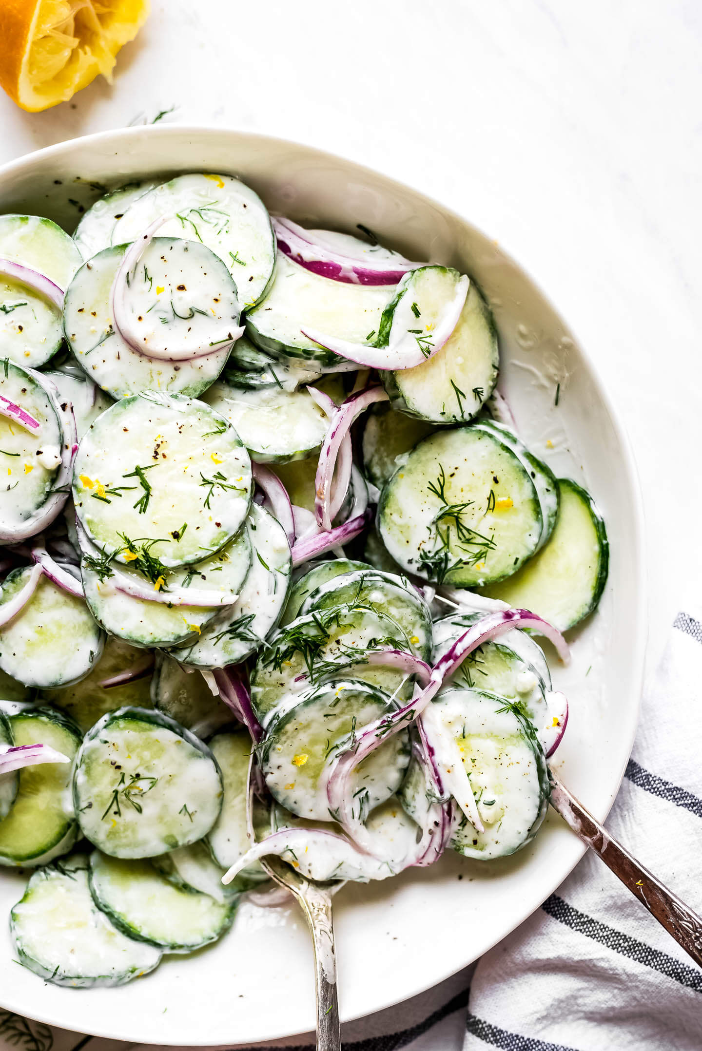 Creamy Cucumber Salad in a large bowl with two spoons scooping some out.