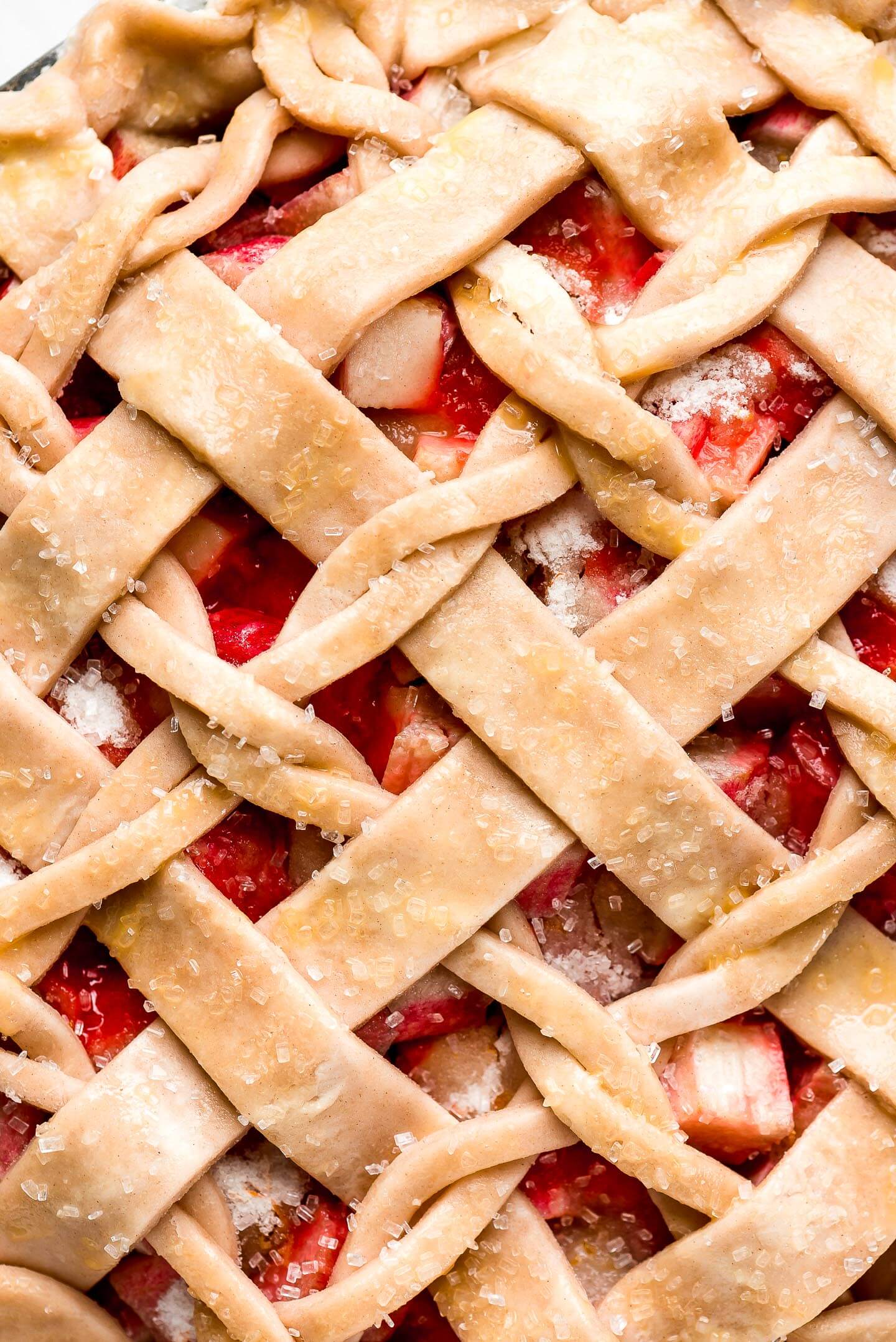 A close up shot of a twist lattice top pie dough with raw rhubarb showing through.
